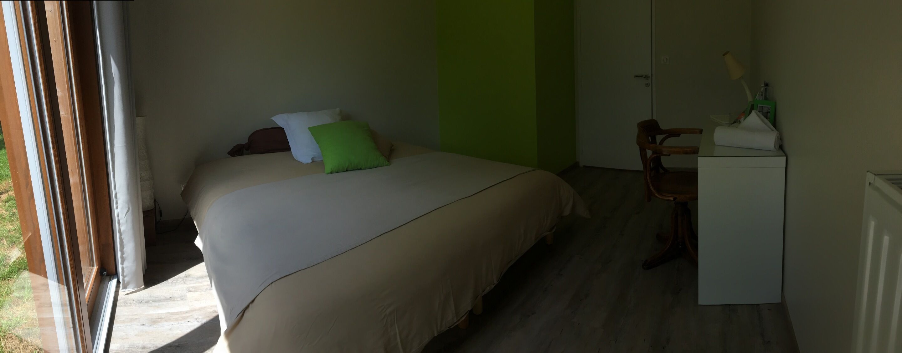 A bedroom with a bed, a desk, and a chair.