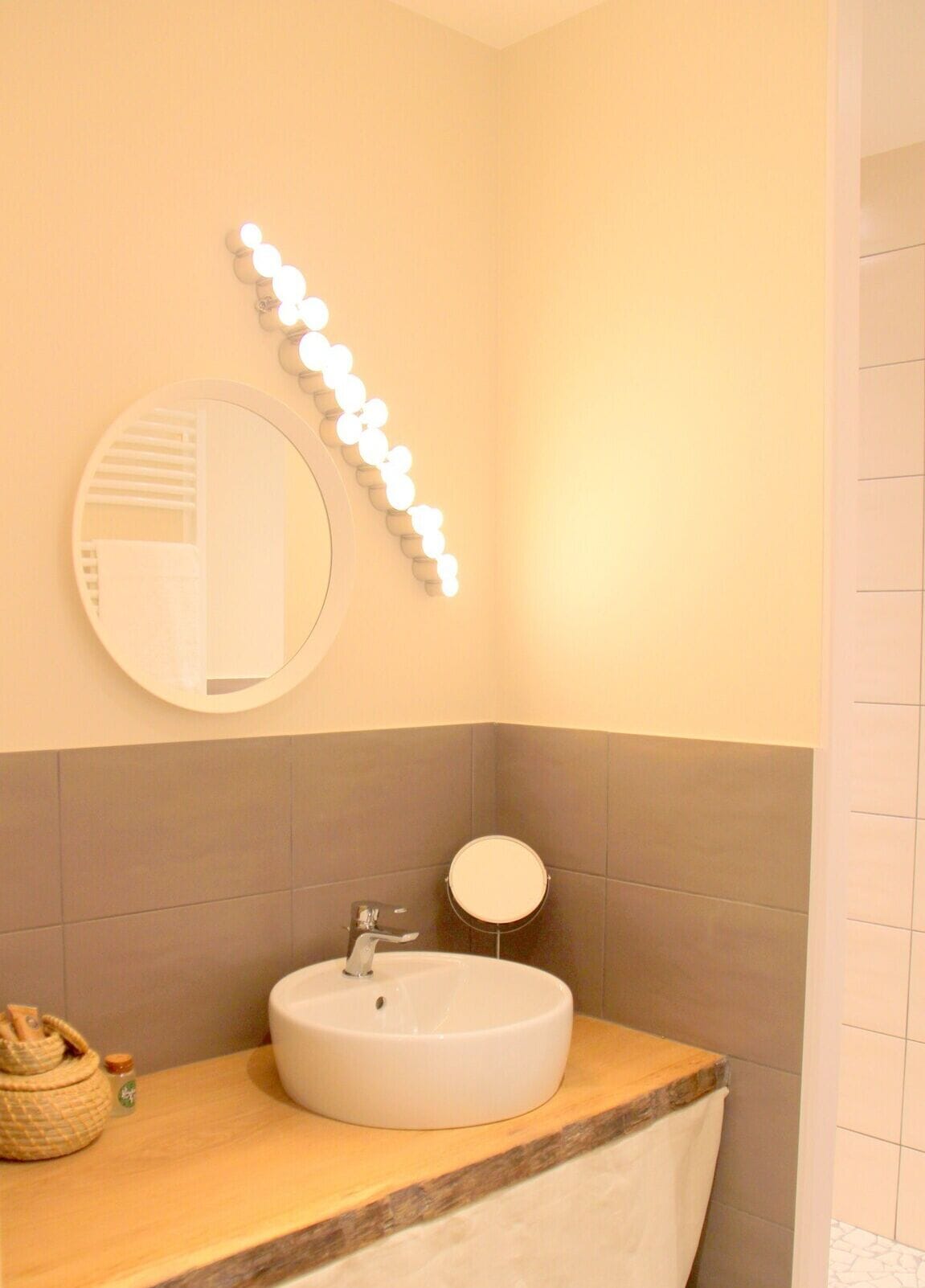 Une salle de bain avec un miroir rond, un lavabo et un meuble-lavabo.