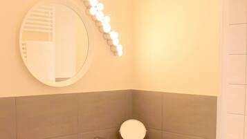 Une salle de bain avec un miroir rond, un lavabo et un meuble-lavabo.