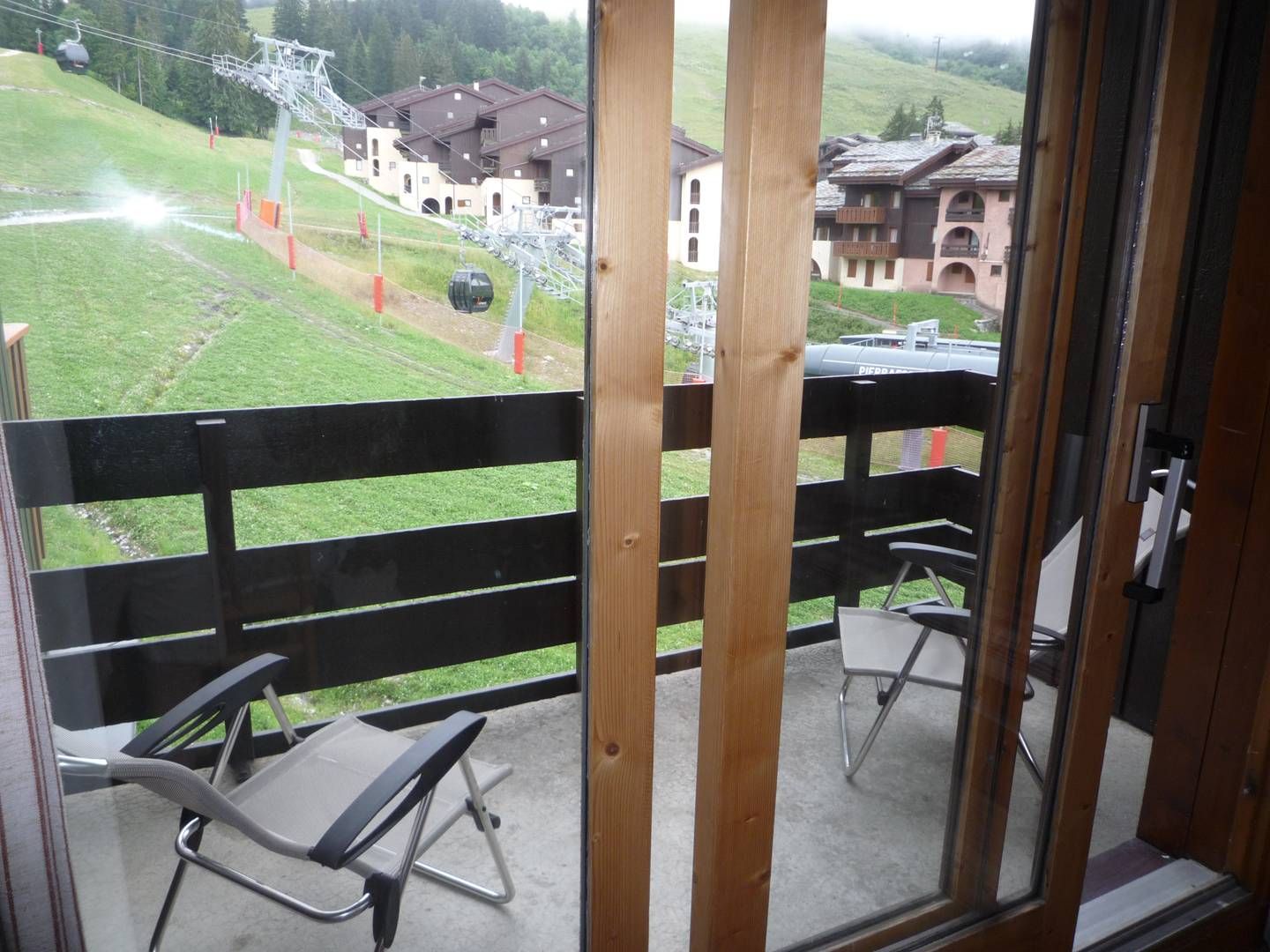 A balcony with a view of a ski lift and buildings in the background.
