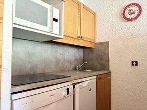 A compact kitchen with a microwave, dishwasher, and wooden cabinets. - Pierrafort 31 - Charming 2-room apartment at the foot of the slopes (LES AVANCHERS VALMOREL)