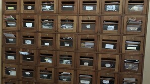 Un archivador de madera con varios cajones, cada uno etiquetado con nombres.