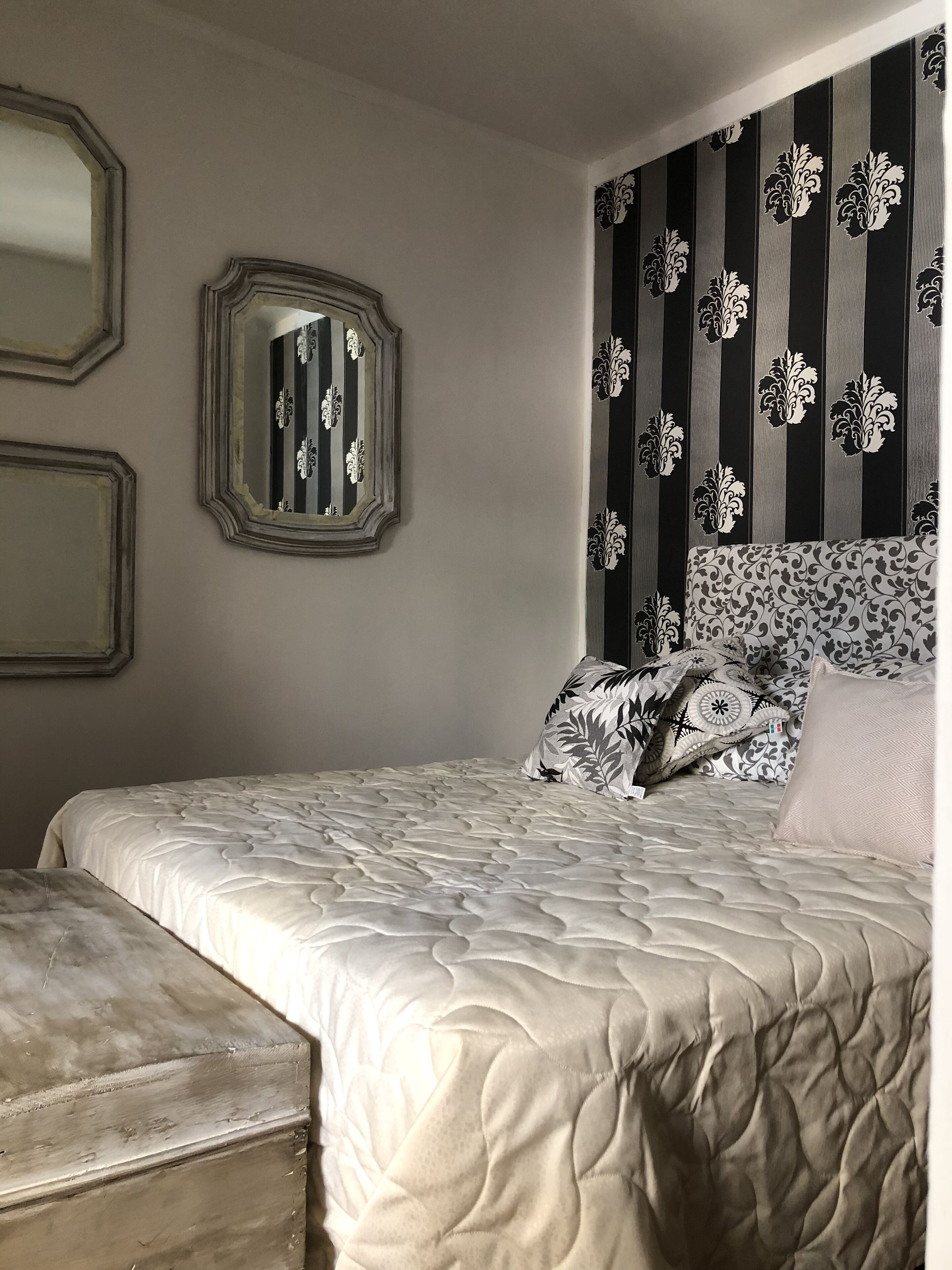 Ein Schlafzimmer mit einem Bett, einem Schminktisch und zwei Wandspiegeln.
