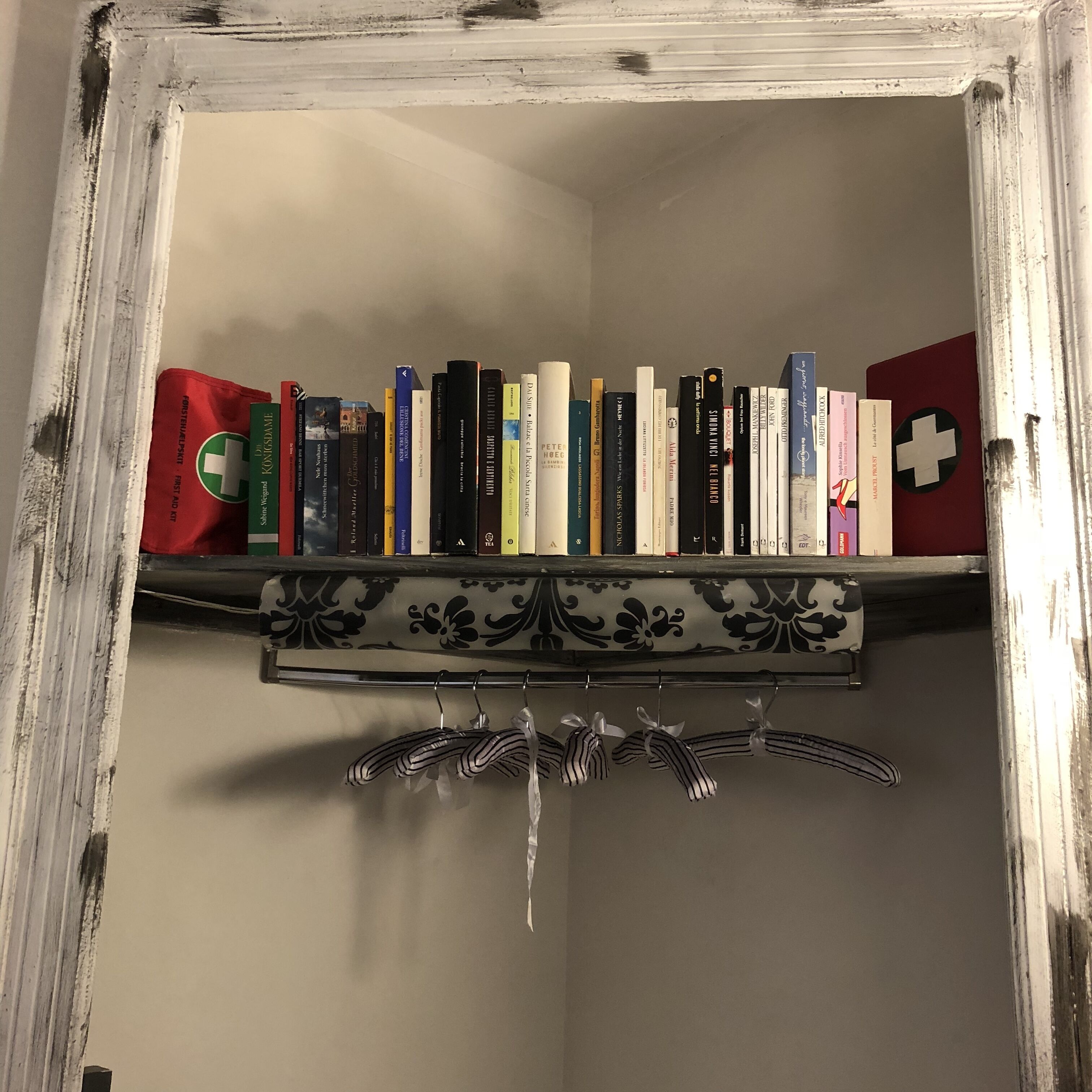 Uma estante com vários livros e um tecido vermelho e verde à esquerda.