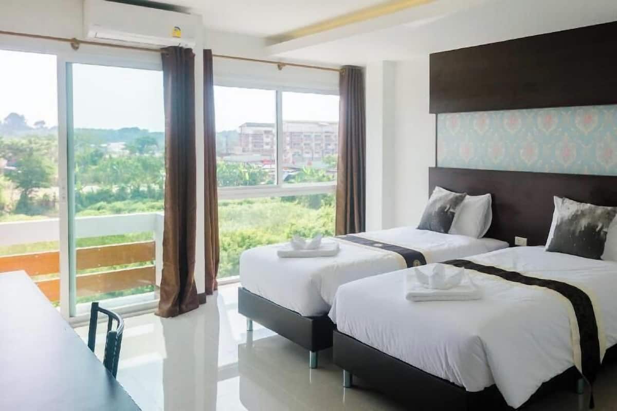 Een hotelkamer met twee bedden, een groot raam met uitzicht, een tafel en een stoel.
