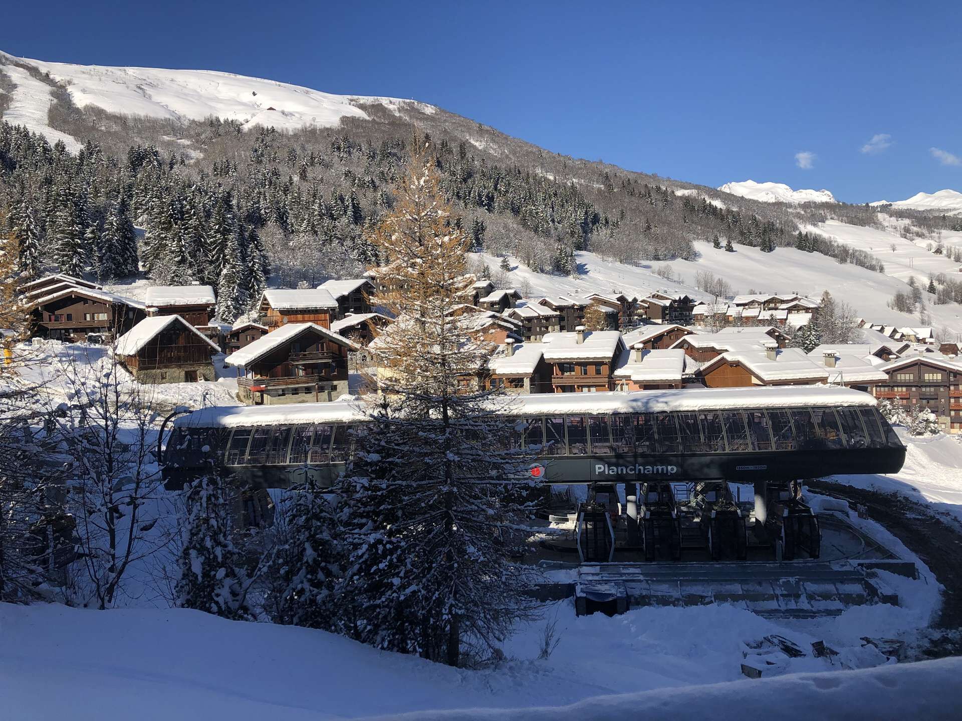 A snow-covered mountain village with wooden buildings and a ski lift.