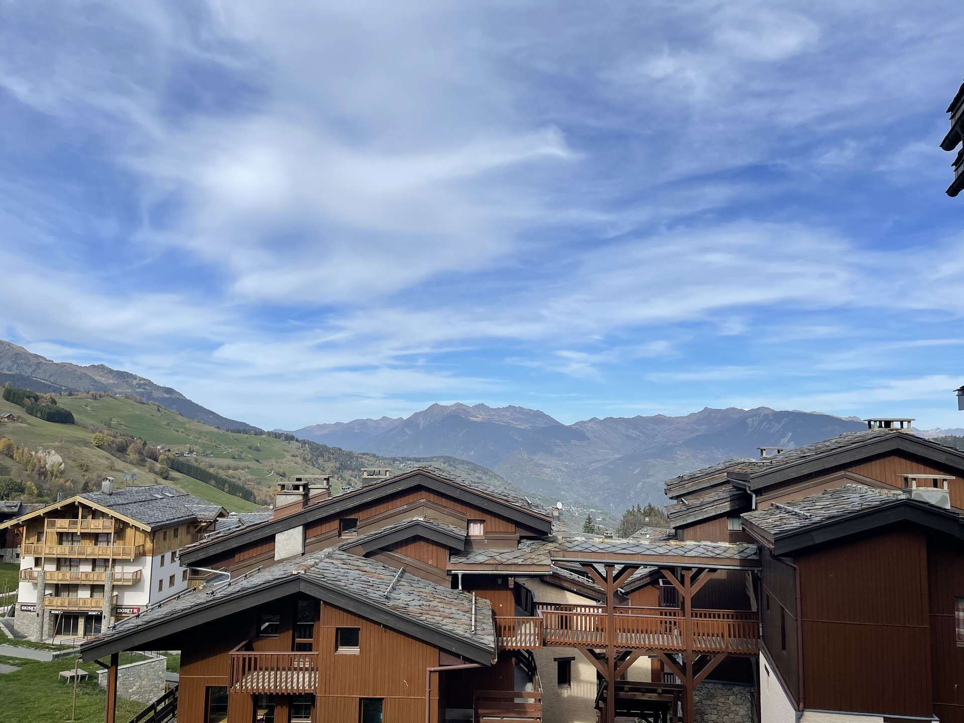 A cluster of wooden chalets with balconies, set against a mountainous backdrop.