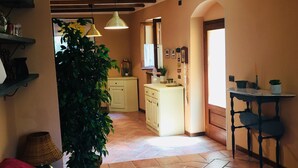Un salon chaleureux avec un canapé rouge, une plante en pot et un sol carrelé.