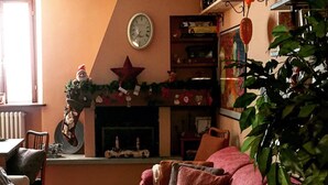 Un salon chaleureux avec une cheminée, un canapé rouge et une grande plante.