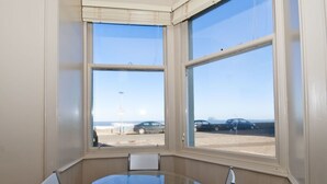 A corner room with a bay window overlooking a parking area and beach. - Seabreeze (North Berwick)