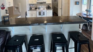A modern kitchen with white cabinets, a central island with bar stools, and pendant lighting.