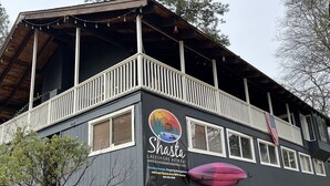 A lakeshore retreat building with a balcony, a signboard, and a kayak.