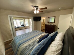 A bedroom with a bed, a ceiling fan, a TV, and a view of the outside. - Best Lakefront Location on Shasta Lake - Marina - Shasta Lakeshore Retreat #3 (Lakehead)