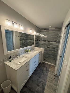 Un bagno moderno con un mobile doppio lavabo, uno specchio grande e una cabina doccia.