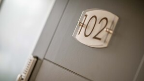 A close-up of a room number sign on a door, indicating room 102. - The James Suites (Londonderry)