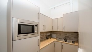 A compact kitchen with a built-in microwave, a toaster, and a sink. - The James Suites (Londonderry)
