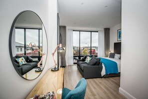 Un moderno cuarto de hotel con un espejo grande, dos sofás, una cama y vista a la ciudad.