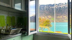 A kitchen with a large window offering a view of a lake and mountains.