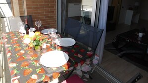 A dining table set for four with a strawberry-themed tablecloth, a bottle of wine, and a vase of flowers. - A207 Apartment in the center of Roses with private parking, near the beach of Roses (Roses, Girona)