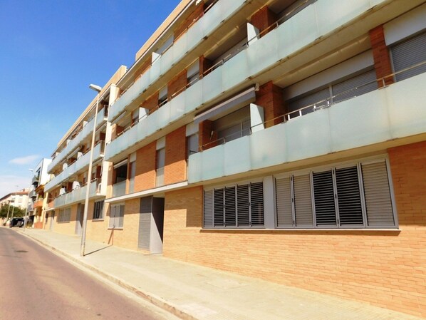 A multi-story residential building with balconies, brick facade, and external shutters. - A207 Apartment in the center of Roses with private parking, near the beach of Roses (Roses, Girona)
