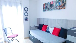A modern bedroom with a bed, a chair, a radiator, and a wall with circular decorations. - A207 Apartment in the center of Roses with private parking, near the beach of Roses (Roses, Girona)