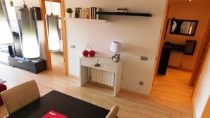 A modern living room with a dining area, a white console table with decorative items, and a bookshelf with books. - A207 Apartment in the center of Roses with private parking, near the beach of Roses (Roses, Girona)