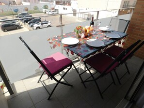 A balcony with a table set for four, featuring a floral tablecloth, plates, cutlery, and a bottle of wine. - A207 Apartment in the center of Roses with private parking, near the beach of Roses (Roses, Girona)