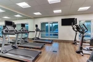 Un gimnasio con cintas de correr, elípticas y bicicletas estáticas.