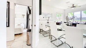 A modern hotel room with a large bed, a bathroom with a mirror and sink, and a dining area with a table and chairs.