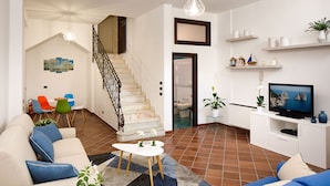 A modern living room with a sofa, a coffee table, and a TV. There is a staircase leading to another room. - Villa Lia (Sant'Agnello)