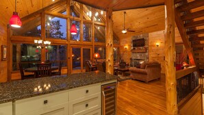 A spacious log cabin interior with a kitchen, dining area, and living room.