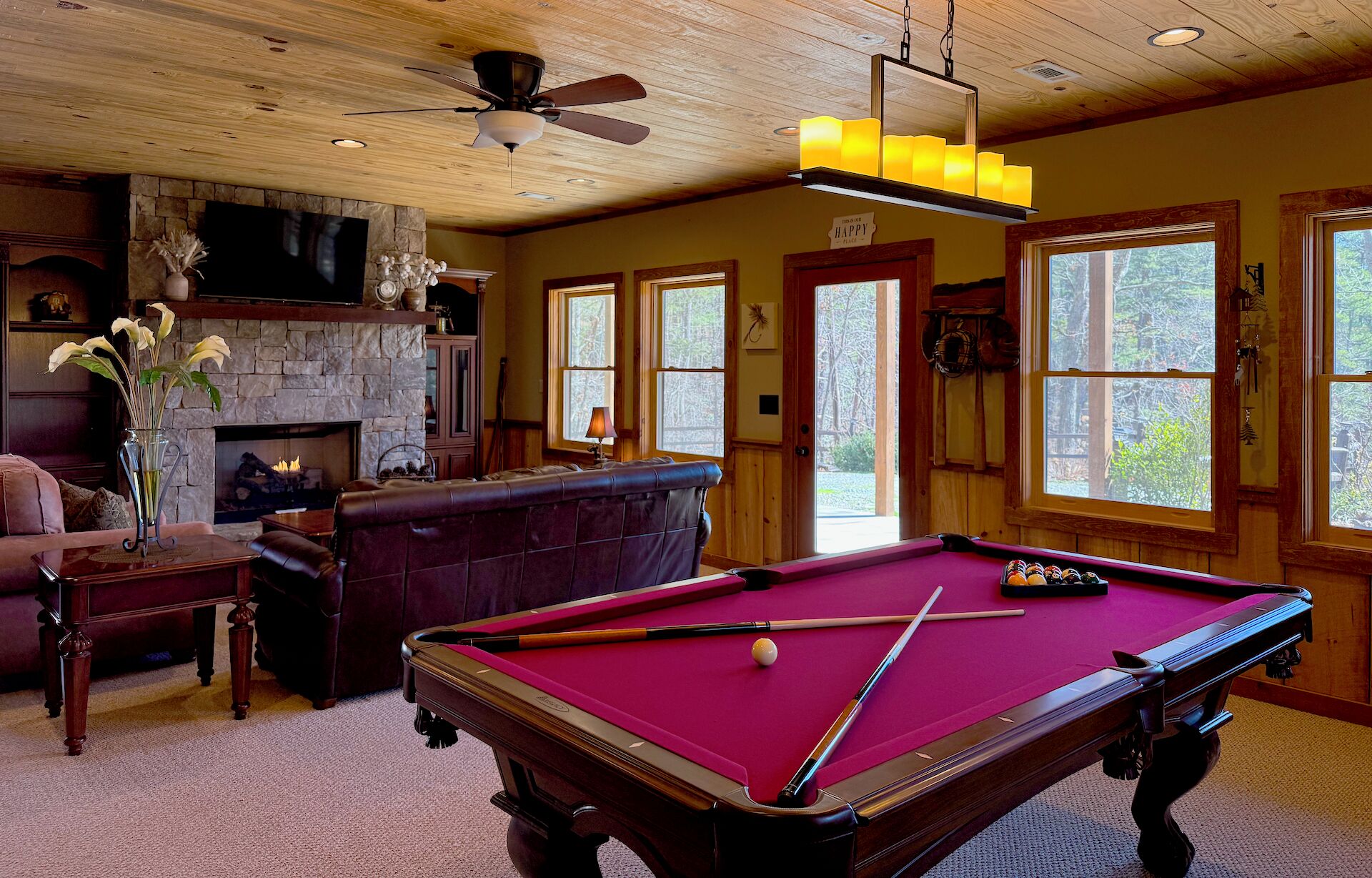 Une pièce chaleureuse avec une table de billard, une cheminée et un coin salon confortable.
