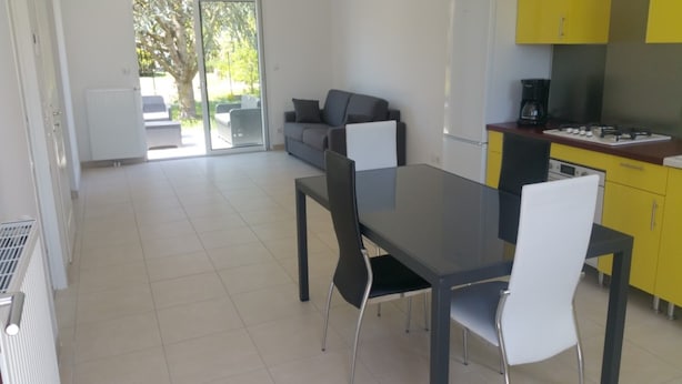 A modern kitchen with yellow cabinets, a dining table with chairs, and a sofa in the background. - House of 50 m2 living space with large landscaped garden (Vineuil)