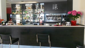 A bar area with a counter, bar stools, a coffee machine, and a variety of bottles and glasses. - HRS Hotel Sabatino (Follonica)