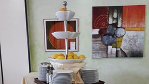 A buffet setup with various food items and a three-tiered fruit bowl. - HRS Hotel Sabatino (Follonica)