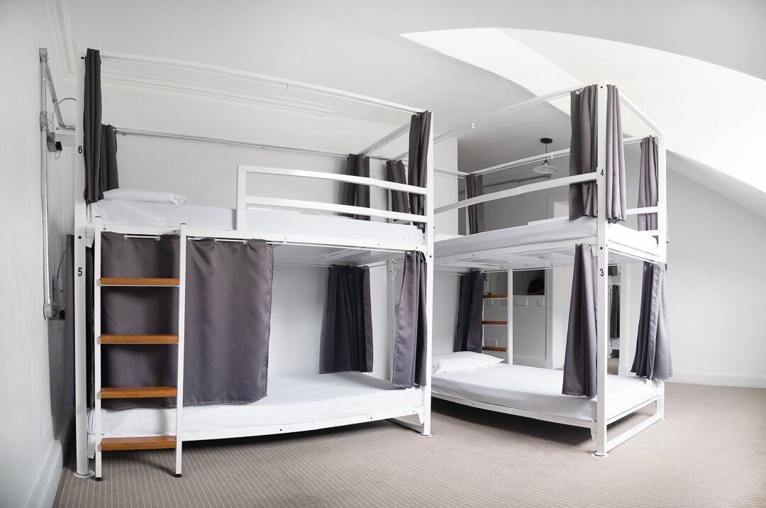 A dormitory-style room with bunk beds, a ladder, and a small closet.