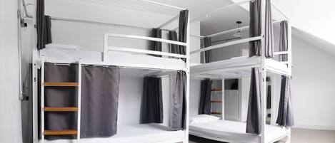 A dormitory-style room with bunk beds, a ladder, and a small closet.