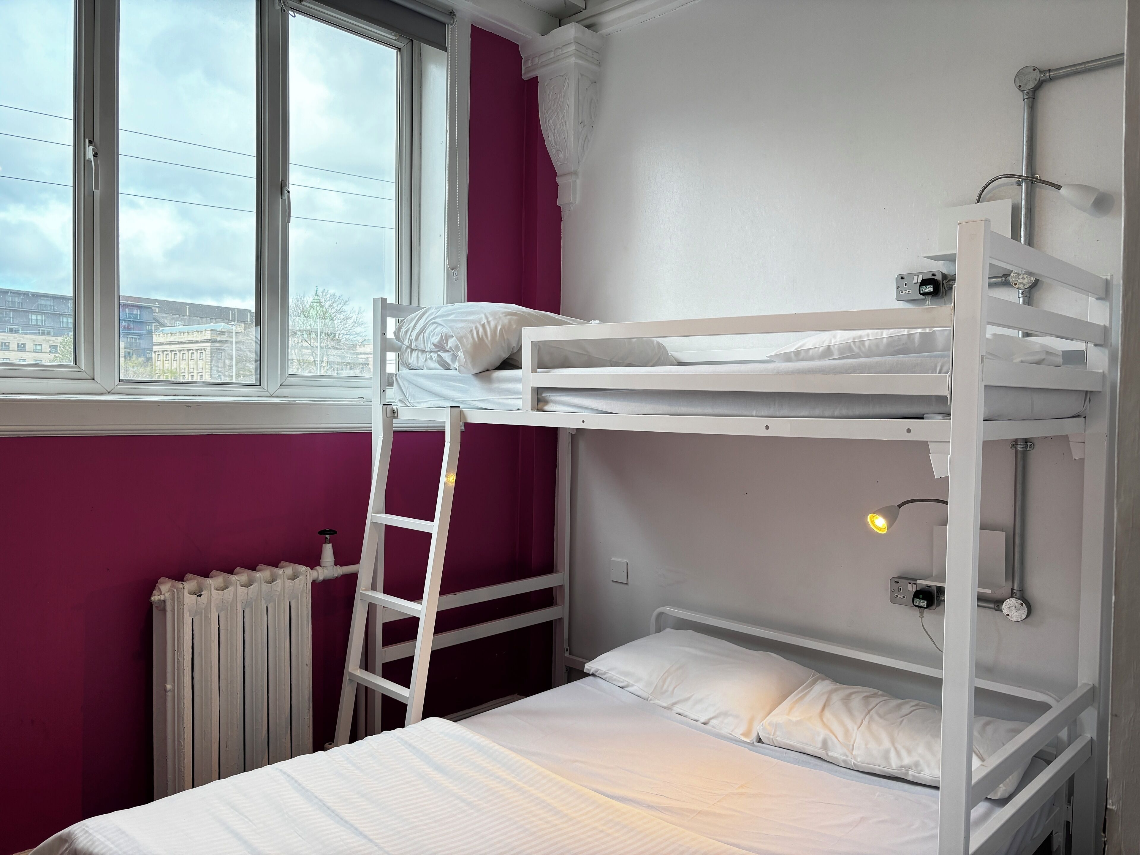 A bunk bed room with a window, a radiator, and a ladder.