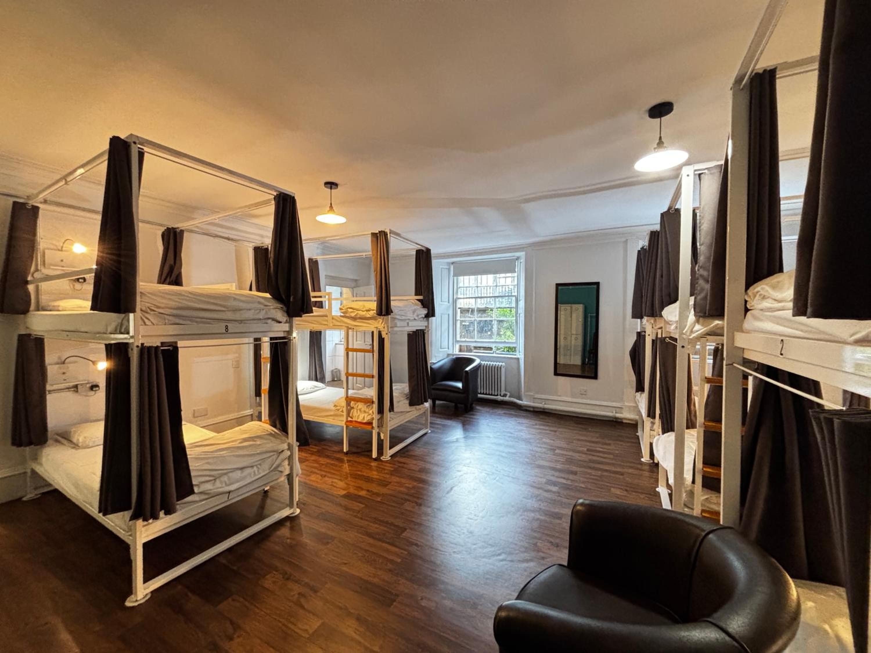 A room with bunk beds, a black leather chair, and a window with a view.