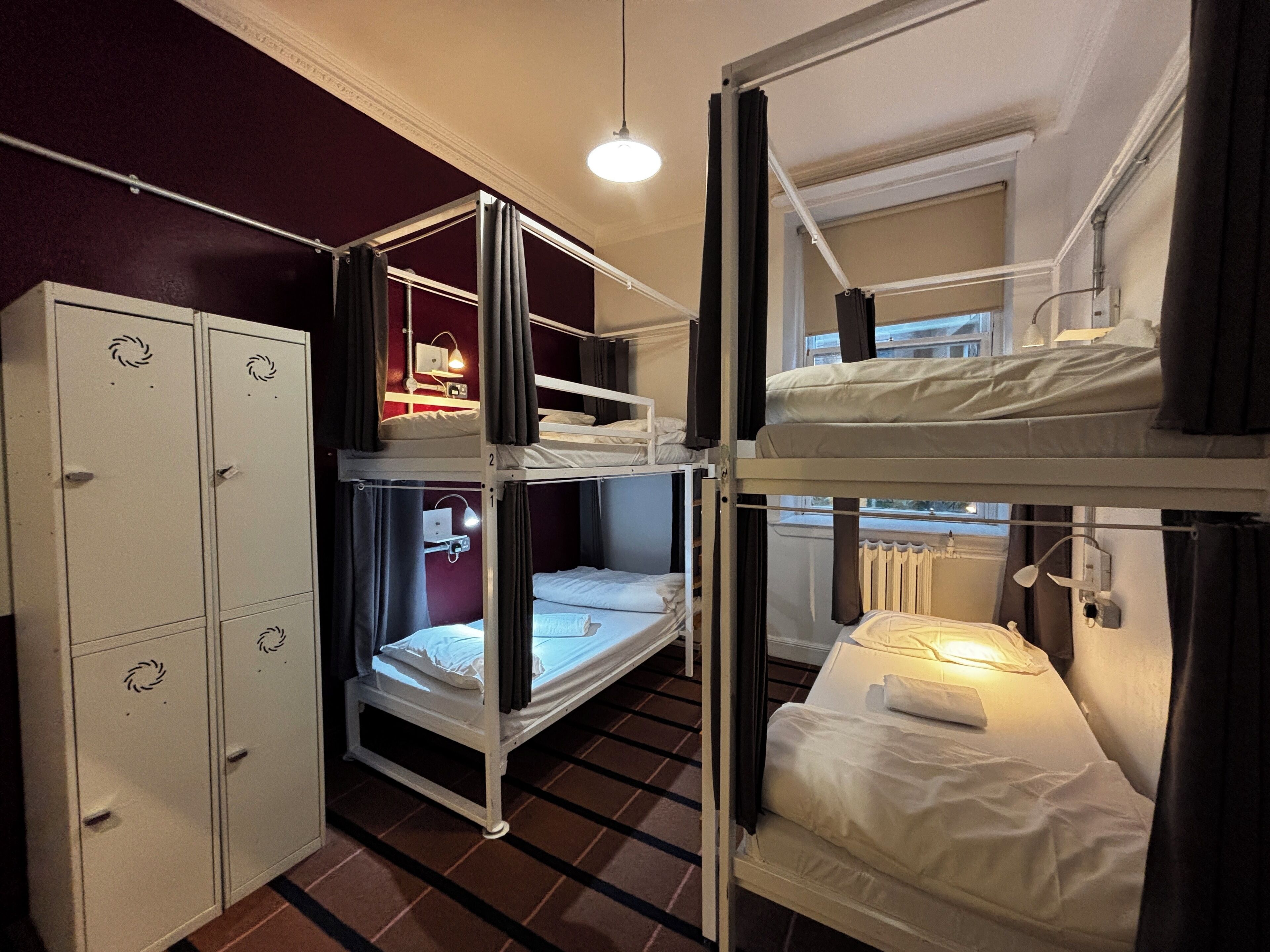 Un dormitorio con literas, un armario y una ventana con cortinas.