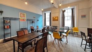 Un comedor con mesas y sillas de madera, una estantería y un mapa mundial en la pared.