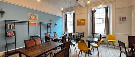 Un coin repas avec des tables et des chaises en bois, une bibliothèque et une carte du monde accrochée au mur.