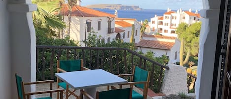 Enjoy the tranquil views of the coastal town from this balcony, featuring a table and four chairs.
