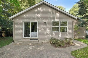 A single-story house with a front porch, a sliding glass door, and a small garden area.