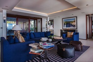 A modern living room with a blue sofa, a coffee table with books, and a large framed picture on the wall.