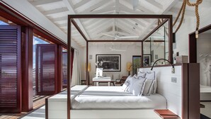 A modern bedroom with a large bed, a wooden ceiling, and a view of the outdoors. - Villa MAISON BLANC BLEU – Iconic Elegance Above Gouverneur (Gustavia)