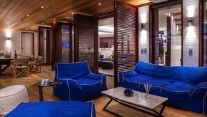 A modern interior with wooden ceiling, blue sofas, a dining area, and a visible kitchen. - Villa MAISON BLANC BLEU – Iconic Elegance Above Gouverneur (Gustavia)