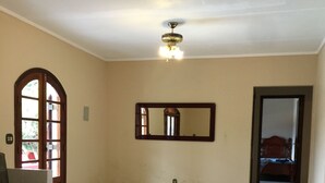 A spacious room with a tiled floor, a ceiling fan, a large mirror, and a door leading to another room. - A Dream in the Mantiqueira Mountains (Itamonte)