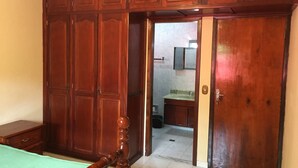 A bedroom with a wooden wardrobe, a bed with a green bedspread, and a bathroom visible through an open door. - A Dream in the Mantiqueira Mountains (Itamonte)