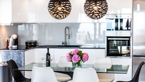 A modern kitchen with white cabinets, a glass dining table, and black chairs.